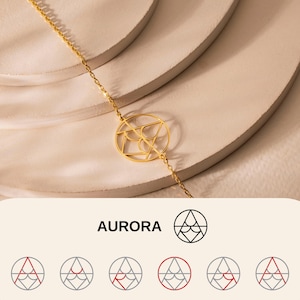 Può includere: Un braccialetto dorato con un pendente geometrico. Il braccialetto ha una catena sottile e un ciondolo circolare con un motivo intricato. La parola "AURORA" è visualizzata in bianco.