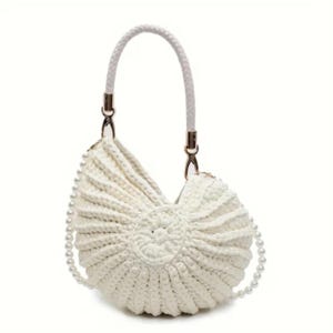 May include: Off-white crochet handbag with a seashell design. Features a braided white handle and a pearl bead chain. The bag has gold-colored metal accents.