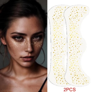 May include: A woman with glitter freckles on her face, next to two clear, star-patterned face stickers. The stickers have a curved shape and are covered in small and large gold stars. The text "2PCS" is at the bottom.