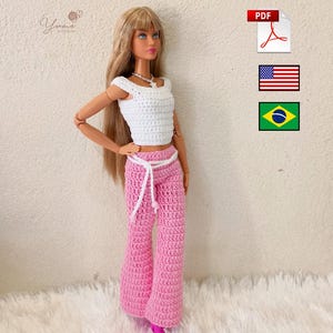 May include: A fashion doll with long blonde hair wearing a white crocheted short-sleeved top and pink crocheted flared trousers with a white tie belt. The image includes a PDF icon, a United States flag icon, and a Brazil flag icon.