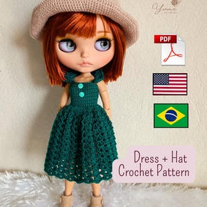 Puede incluir: Una muñeca de pelo rojo con un sombrero de ganchillo beige y un vestido de ganchillo verde oscuro con dos botones pequeños en el corpiño. La imagen incluye un icono de PDF, banderas de EE. UU. y Brasil, y el texto Dress + Hat Crochet Pattern.