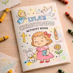 Peut inclure: Un livre d'activités pour enfants intitulé "Lyla's Christening", avec des illustrations d'un ange, d'une colombe, d'une croix, d'une bougie, d'une fleur et d'une fille. Des crayons entourent le livre.