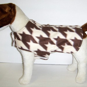 May include: A white and brown houndstooth dog sweater with a zipper closure.