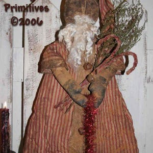 Könnte beinhalten: Eine rustikale Weihnachtsmann-Puppe mit langem weißem Bart, bekleidet mit einem rot-beige gestreiften Mantel und Hut. Die Puppe hält Grünzeug und Zuckerstangen. Der Text "Tennessee Ridge Primitives ©2006" ist sichtbar.