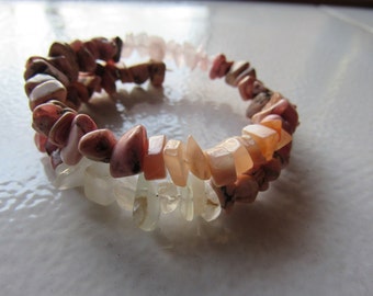 May include: A bracelet made of pink, white, and peach colored gemstone chips. The bracelet is made of natural stones and is a beautiful and unique piece of jewelry.