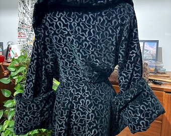 May include: A black velvet jacket with a hood and long sleeves. The jacket has a swirling pattern throughout.