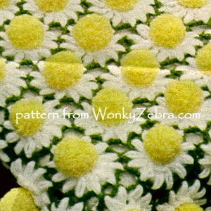 May include: Close-up of a white fabric with a daisy pattern. Each daisy has white petals and a yellow center. Green leaves are visible between the flowers. The text "pattern from WonkyZebra.com" is in the image.