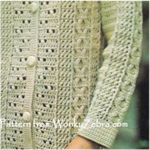 May include: A crocheted cardigan with a button-up front and a lacy pattern. The cardigan is a light cream color and has a textured stitch.