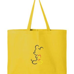 May include: Yellow tote bag with black, red, and yellow Mickey Mouse outline design. The bag has long yellow handles and is made of a solid yellow material. The tote bag is a simple, yet stylish accessory.