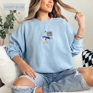 May include: Light blue sweatshirt with a graphic of a goose holding a gun, with the text "HONK! HONK! MOTHER F***ERS". The words "LIGHT BLUE" are in the upper left corner.