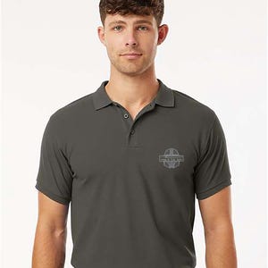 K&ouml;nnte beinhalten: Dunkelgraues Poloshirt mit kurzen &Auml;rmeln und Kragen. Das Shirt hat eine kleine, hellgraue Grafik auf der Brust mit dem Text "THIS IS THE WAY". Das Shirt hat ein klassisches Design mit Kn&ouml;pfen und ist aus weichem Material gefertigt.