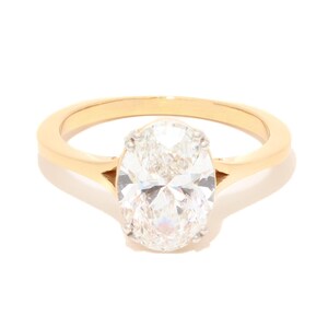 May include: A gold engagement ring with a large, oval-cut diamond. The diamond is set in a classic four-prong setting, and the band is a simple, polished gold. The ring is displayed on a white background.