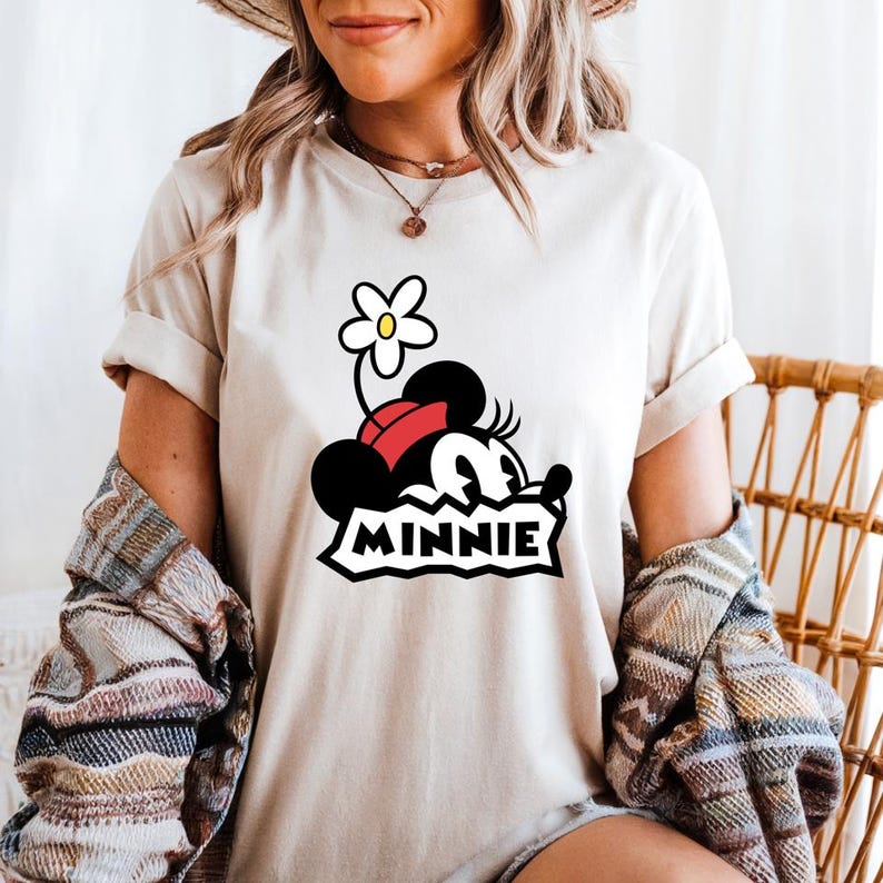 May include: White t-shirt with a cartoon image of Minnie Mouse wearing a red bow and a flower on her head. The text "MINNIE" is printed below the image.
