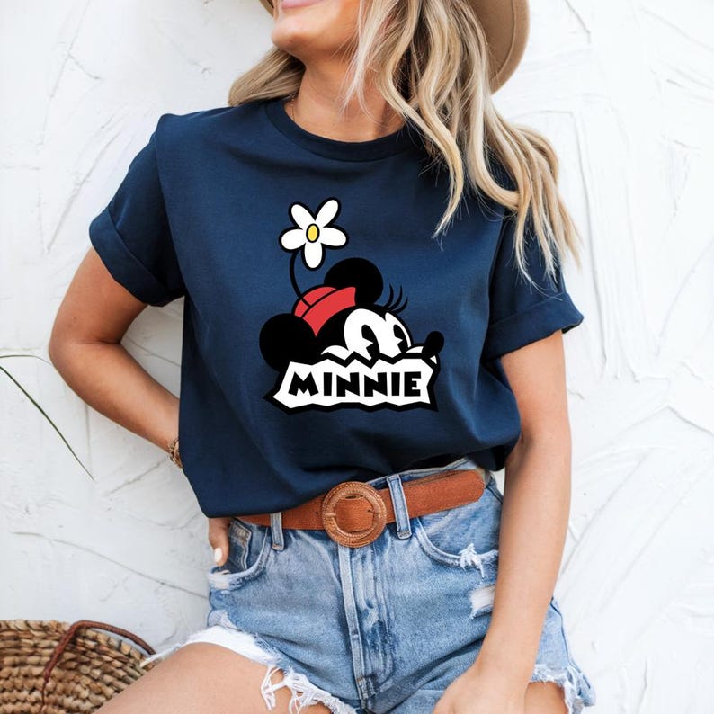 May include: A navy blue t-shirt with a cartoon image of Minnie Mouse wearing a red bow and a white flower. The text "MINNIE" is printed below the image.