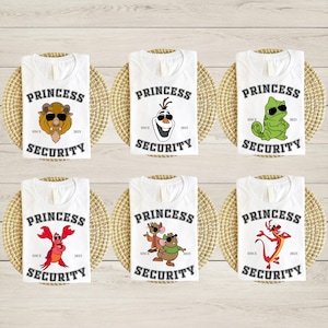 May include: White t-shirts with various cartoon character graphics, including a beast, Olaf, a chameleon, a lobster, mice, and Mushu. Each shirt has the text "PRINCESS SECURITY" and "SINCE 2025". The shirts are displayed on woven mats.