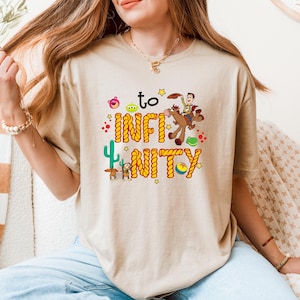 May include: A beige t-shirt with a graphic of Woody from Toy Story riding a horse with the text "to infinity and beyond" in a rope design.
