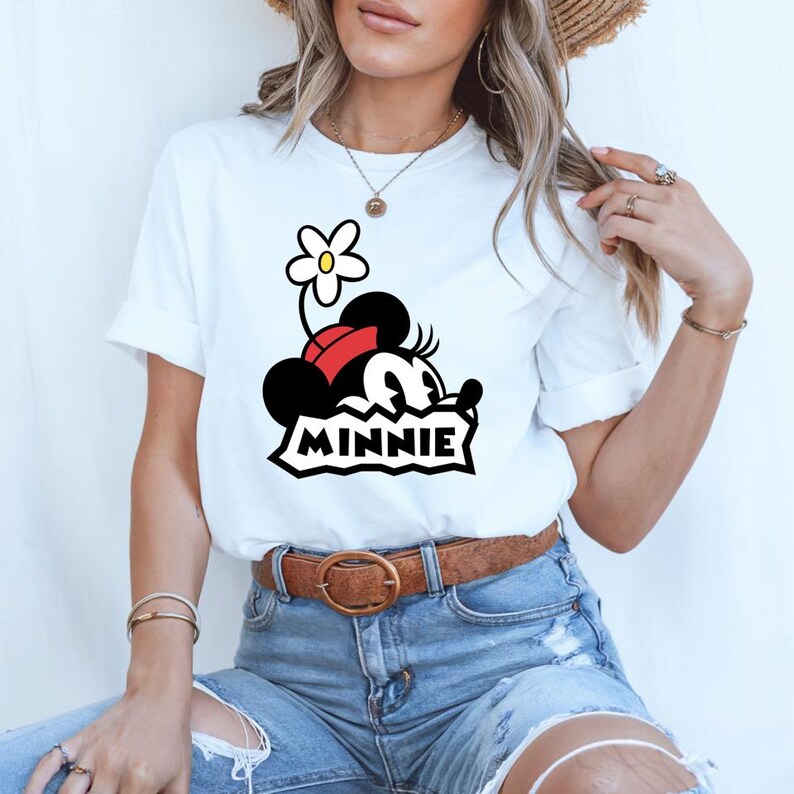 May include: White t-shirt with a cartoon image of Minnie Mouse wearing a red bow and a flower on her head. The text "MINNIE" is printed below the image.