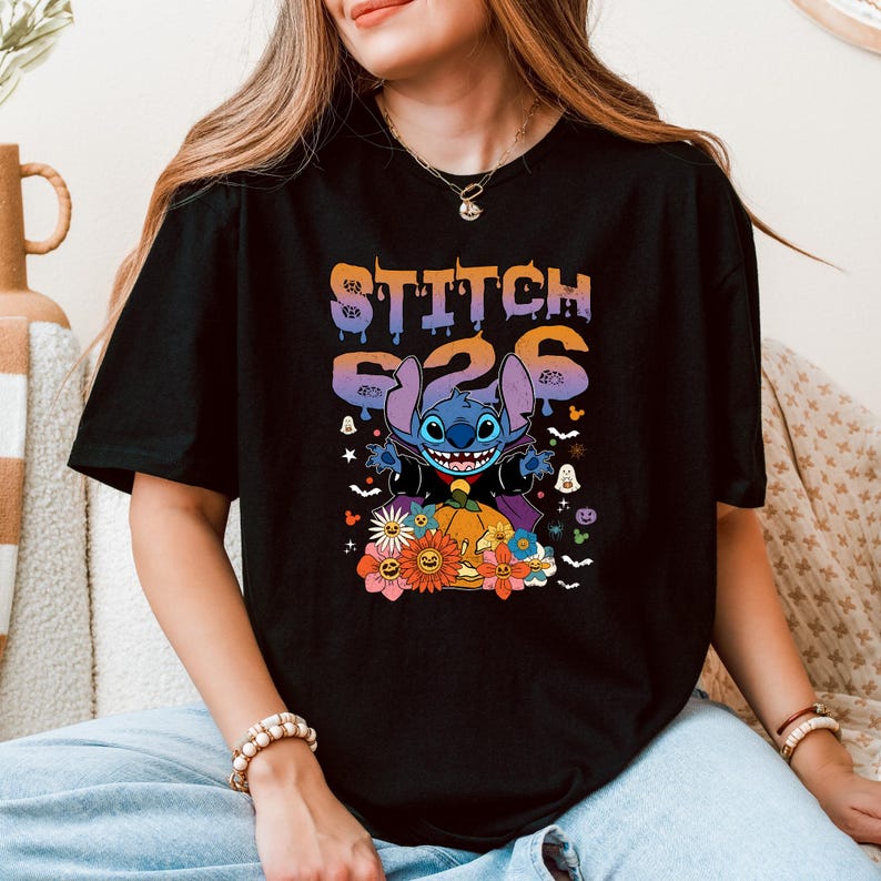 Puede incluir: Camiseta negra con un gr&aacute;fico colorido de Stitch de Lilo & Stitch. El dise&ntilde;o incluye el texto "STITCH 626" encima de Stitch, rodeado de elementos tem&aacute;ticos de Halloween como calabazas, flores y fantasmas.
