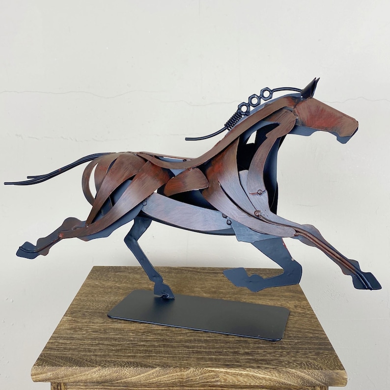 May include: A metal sculpture of a horse in mid-gallop. The sculpture is made of various metal pieces, with a color palette of brown, gray, and black. The horse is mounted on a black rectangular base.