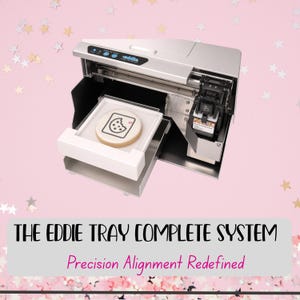 May include: A silver and black food printer with a white tray holding a cookie decorated with a cookie graphic. The image includes the text "THE EDDIE TRAY COMPLETE SYSTEM" and "Precision Alignment Redefined" on a pink background with star confetti.