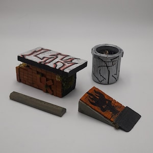 Puede incluir: Elementos de diorama urbano en miniatura. Incluye un edificio de ladrillo con graffiti, un cubo de basura, un bloque de hormigón y una rampa de ladrillo con un diseño negro. Las piezas son de ladrillo y hormigón.