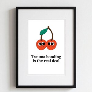 Może przedstawiać: Oprawiony wydruk artystyczny z kreskówkową ilustracją dwóch wiśni z uśmiechniętymi twarzami i zielonym liściem. Tekst "Trauma bonding is the real deal" jest wydrukowany pod wiśniami czcionką.