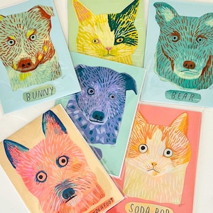 May include: A collection of colorful art prints featuring stylized animal portraits. The prints include a dog labeled "Bunny", a cat, a bear, a dog labeled "Underfoot", a purple dog, and a cat labeled "Soda Pop". Each print has a unique color palette.