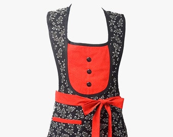 May include: A black and red apron with a white floral pattern. The apron has a red ribbon tie and a red pocket. The apron has a ruffled hem.