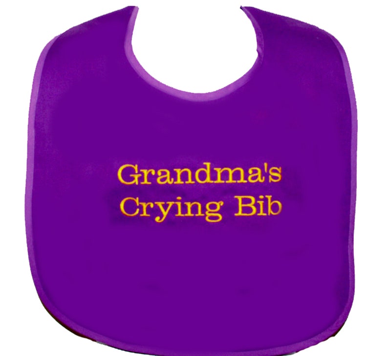 May include: Purple baby bib with yellow embroidery that reads "Grandma's Crying Bib".