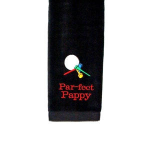 May include: Black golf towel with a white golf ball and golf tees embroidered on it. The text "Par-fect Pappy" is embroidered in red.