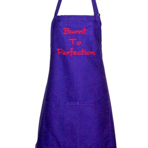 Pode incluir: Avental roxo com o texto "Burnt To Perfection" bordado em vermelho. Possui um bolso e uma al&ccedil;a de pesco&ccedil;o ajust&aacute;vel. Acess&oacute;rio de cozinha para cozinhar e assar.