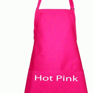 Pode incluir: Um avental rosa choque com um bolso e uma al&ccedil;a de pesco&ccedil;o ajust&aacute;vel. As palavras "Hot Pink" est&atilde;o impressas em branco na frente. O avental &eacute; feito de um tecido rosa brilhante s&oacute;lido.