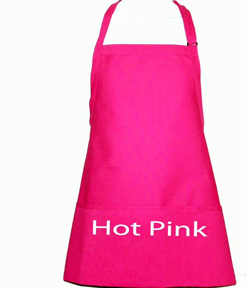 Pode incluir: Um avental rosa choque com um bolso e uma al&ccedil;a de pesco&ccedil;o ajust&aacute;vel. As palavras "Hot Pink" est&atilde;o impressas em branco na frente. O avental &eacute; feito de um tecido rosa brilhante s&oacute;lido.