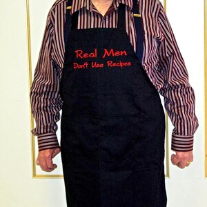 May include: A black apron with red embroidered text that reads "Real Men Don't Use Recipes".