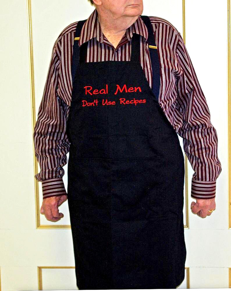 May include: A black apron with red embroidered text that reads "Real Men Don't Use Recipes".