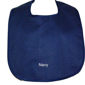 May include: A navy blue bib with a rounded neckline and a simple design. The bib has the word "Navy" embroidered on the front.