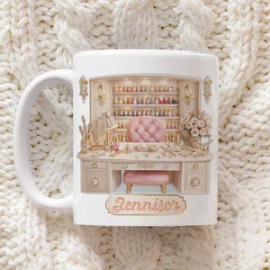 May include: White ceramic mug with a detailed illustration of a nail salon desk. The design includes a pink tufted chair, a shelf of nail polish bottles, and the name "Jennifer". The mug has a white handle.