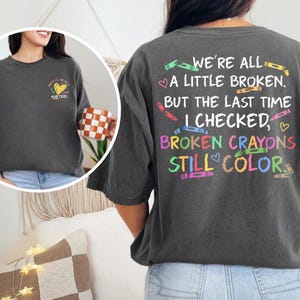 May include: Dark gray t-shirt with the text "Mental Health Matters" on the front and "We're All A Little Broken, But The Last Time I Checked, Broken Crayons Still Color" on the back. The back design includes colorful crayon illustrations.