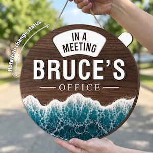 May include: A round wooden sign with a dark wood grain finish featuring the text IN A MEETING and BRUCE'S OFFICE in white and dark brown lettering. The bottom section displays a realistic ocean wave graphic with white sea foam and blue water.