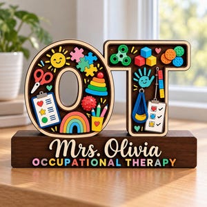 May include: A wooden desk sign featuring the letters OT filled with colorful icons including a sun, puzzle pieces, scissors, a clipboard, a rainbow, a spinner, blocks, a hand, and a checklist. The base displays the text Mrs. Olivia OCCUPATIONAL THERAPY.