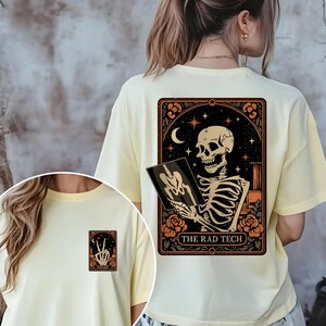 Back design of the Halloween rad tech shirt displaying a detailed skeleton doing an X-ray gesture surrounded by moon and floral motifs. Printed on a burnt orange tee, this makes a stylish and festive gift for radiology or imaging professionals.
