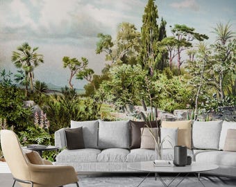 May include: A living room scene featuring a large, light gray sofa with several throw pillows in shades of brown and beige. A round, white coffee table sits in front of the sofa. The backdrop is a mural depicting a lush, green landscape with trees and a cloudy sky.