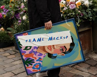 Puede incluir: Una impresión artística enmarcada con una colorida ilustración del rostro de una mujer, con maquillaje llamativo y una parte superior estampada. El marco azul contiene la obra de arte, parcialmente cubierta por una pancarta blanca con el texto "FRAME MOCKUP".