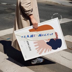 May include: A white frame mockup with a colorful abstract design. The text "FRAME MOCKUP" and "JERN LOVE" is visible on the frame. The frame is being held by a person.