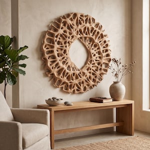 May include: A large, circular wall sculpture featuring an intricate, organic, web-like lattice pattern in a light tan wood tone. The piece has a hollow centre and a textured, porous appearance, mounted centrally on a plain, neutral-coloured wall.