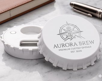 Puede incluir: Un abridor de botellas circular blanco con un borde dentado que recuerda a una chapa. La parte superior presenta un logotipo gris con una brújula, una espiga de trigo y montañas, con el texto AURORA BREW PREMIUM CUSTOM OPENER EST. 2024.