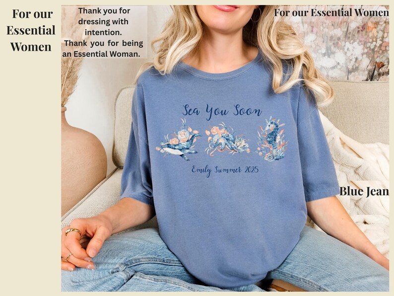 May include: A blue jean colored t-shirt featuring a graphic print with the text Sea You Soon and Emily Summer 2025. The design includes illustrations of a whale, an octopus, and a seahorse surrounded by floral elements in shades of blue and peach.