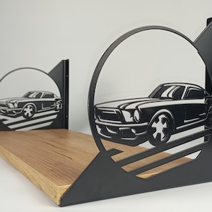 May include: A black metal shelf with a classic car silhouette design. The shelf has a natural wood base and is supported by two black metal brackets. The car design is cut out within a circular frame.