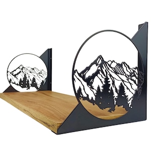 Puede incluir: Estante de madera con recortes de escena de montaña de metal negro. El estante tiene un acabado de madera natural y está soportado por soportes de metal negro. La escena de la montaña es una silueta de picos y árboles.