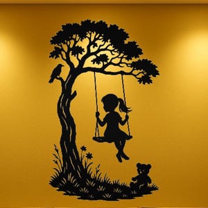 Könnte beinhalten: Schwarze Silhouette Wandkunst eines Mädchens auf einer Schaukel unter einem Baum mit einem Vogel auf einem Ast. Ein Teddybär sitzt unten auf dem Gras. Das Kunstwerk ist vor einem goldgelben Hintergrund platziert.